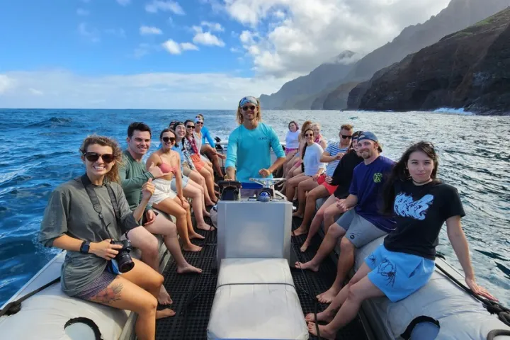 A Group of Boat Tour Passengers having a good time with the Sellout of the Na Pali Coast Cliffs In the background