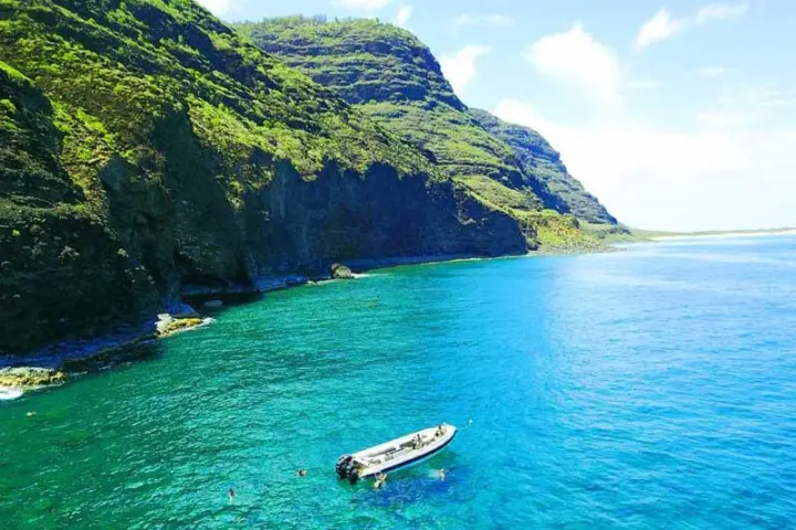 A Group of Snorkelers in clear water with Polihale State Park in the background