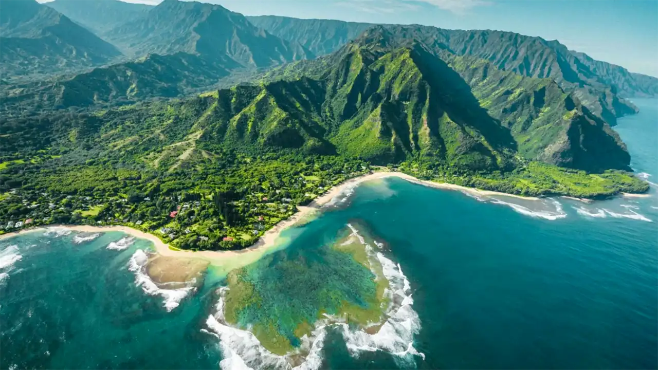 Aerial view of a lush, green mountainous coastline with sandy beaches and turquoise waters.