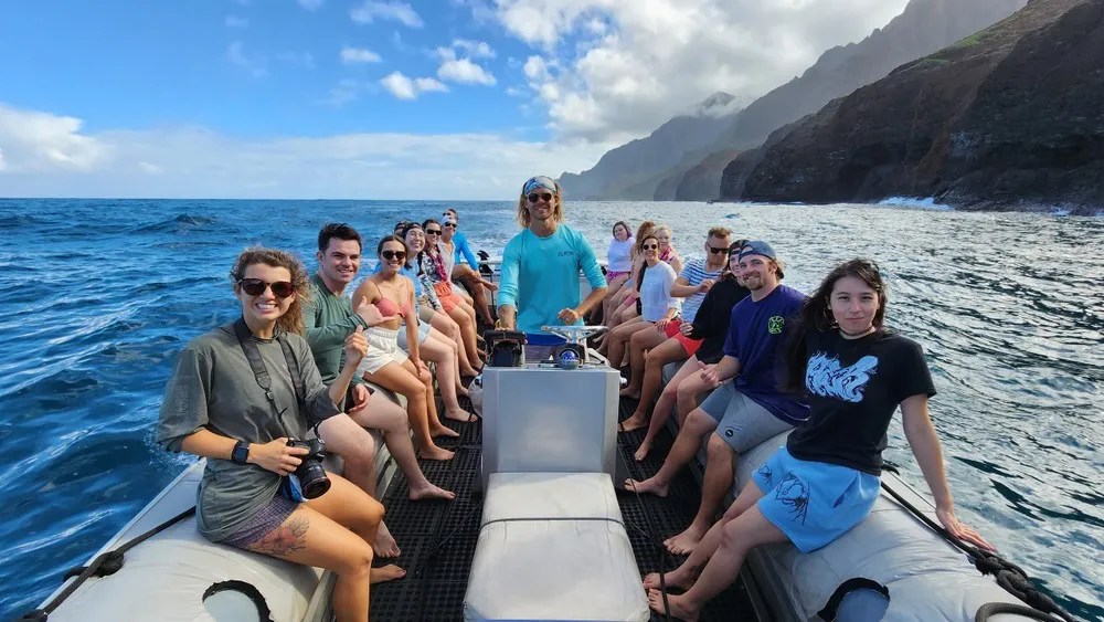Group on a boat tour with mountains in the background.